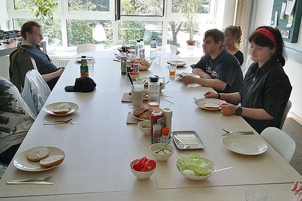 Tagesgruppe Adoleszenz -Kochprojekt - Teilnehmenden sitzen gemeinsam am Tisch und frühstücken